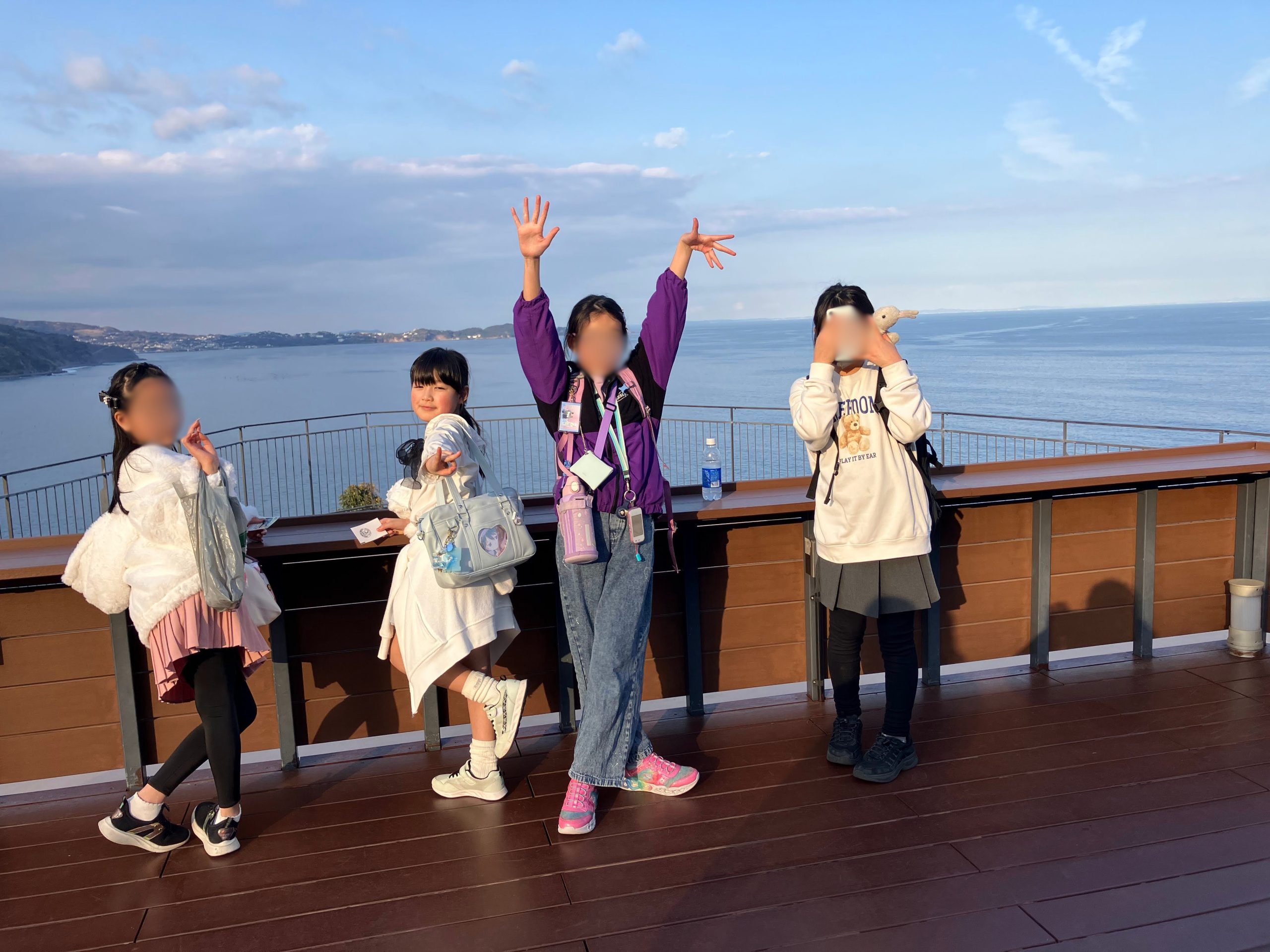 熱海城の展望台で海をバックに仲間と並んで記念撮影するaini school小中等部の生徒たち