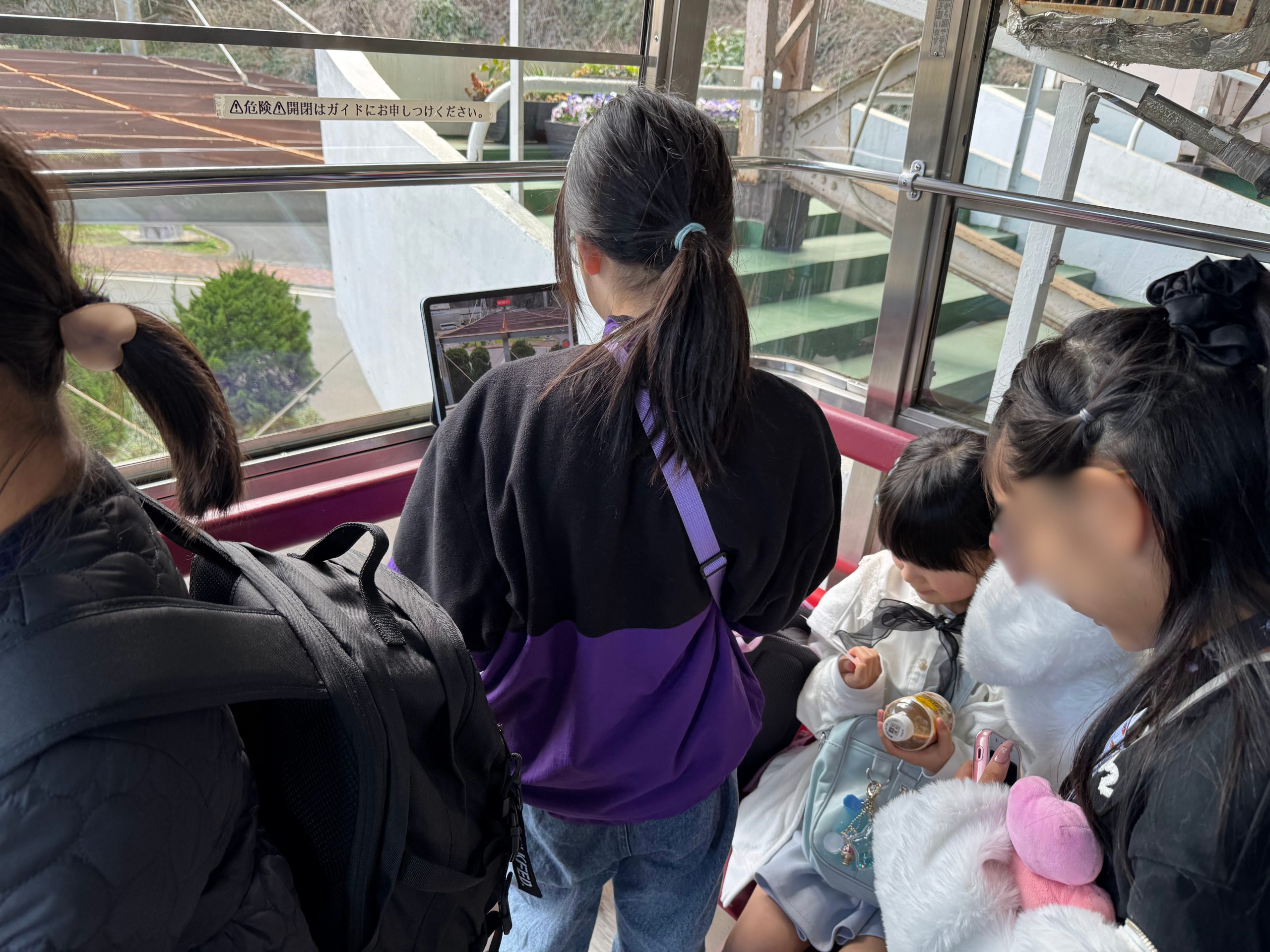 ロープウェイの車内から外をのぞき込みながら話し続けるaini schoolの子どもたち