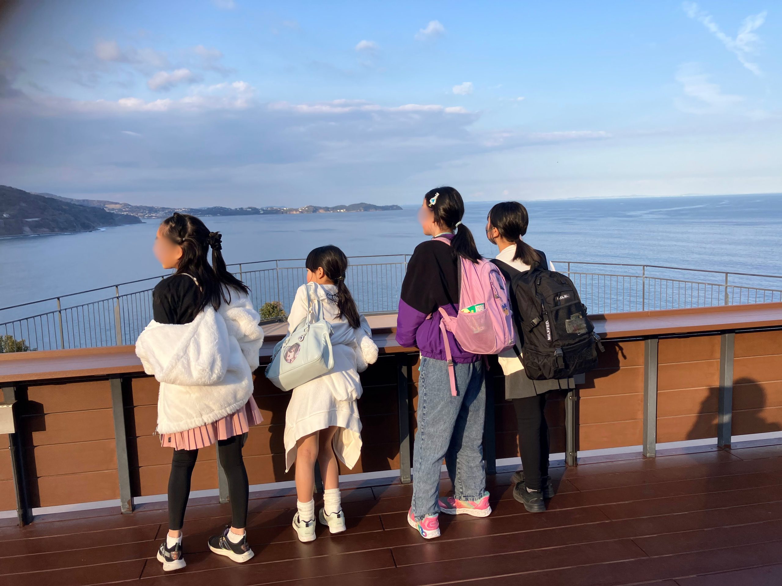 熱海城の展望台から海を見下ろす子どもたちの後ろ姿。眼下に熱海の街と相模湾が広がる