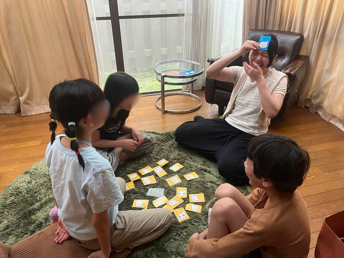 alt属性aini school 現地通学校(保谷校)で、クラスガイドと子どもたちがカードゲームで楽しむ様子。