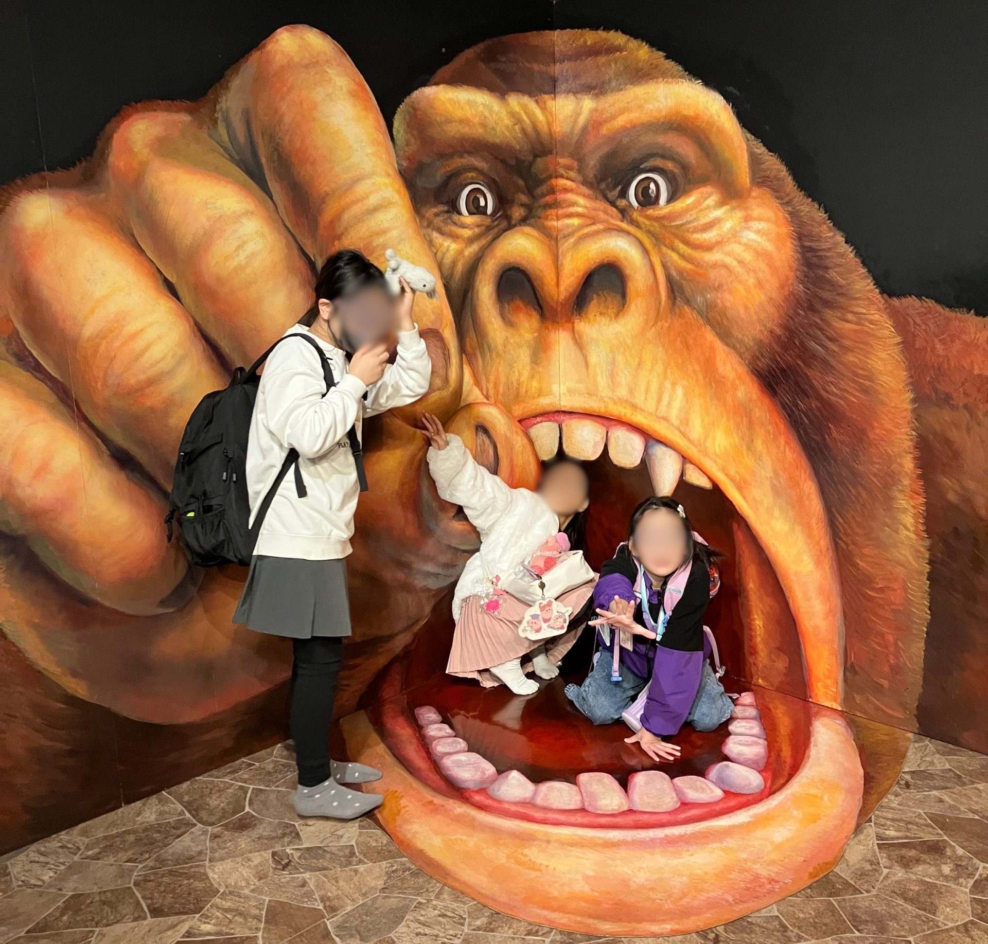 ゴリラの口の中に飛び込むトリックアートの前で大はしゃぎするaini schoolの生徒たち