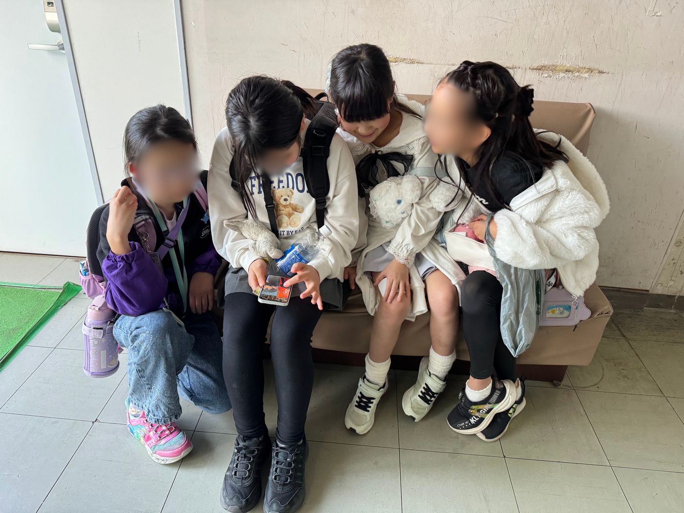 帰り道のソファで4人寄り添って写真を見せ合うaini schoolの子どもたち。すっかり打ち解けた様子