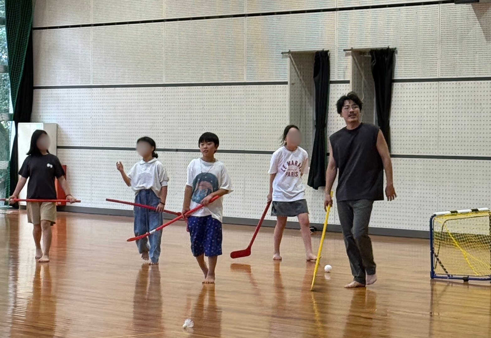 修学旅行の体育館でフロアホッケーを楽しむ小学生・中学生たち