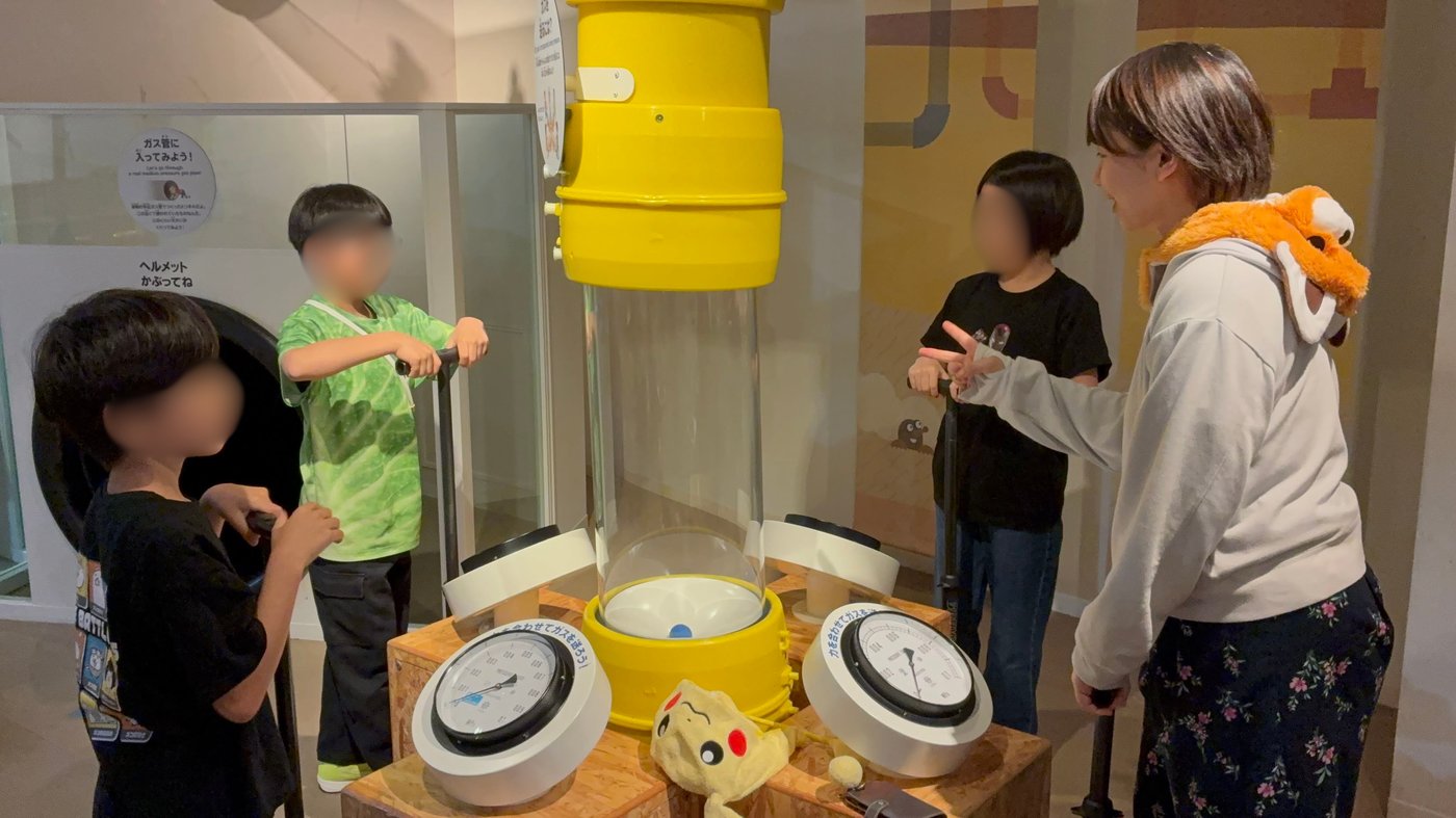 圧力計のついた装置を手で押してガスの仕組みを体験するaini schoolの子どもたち