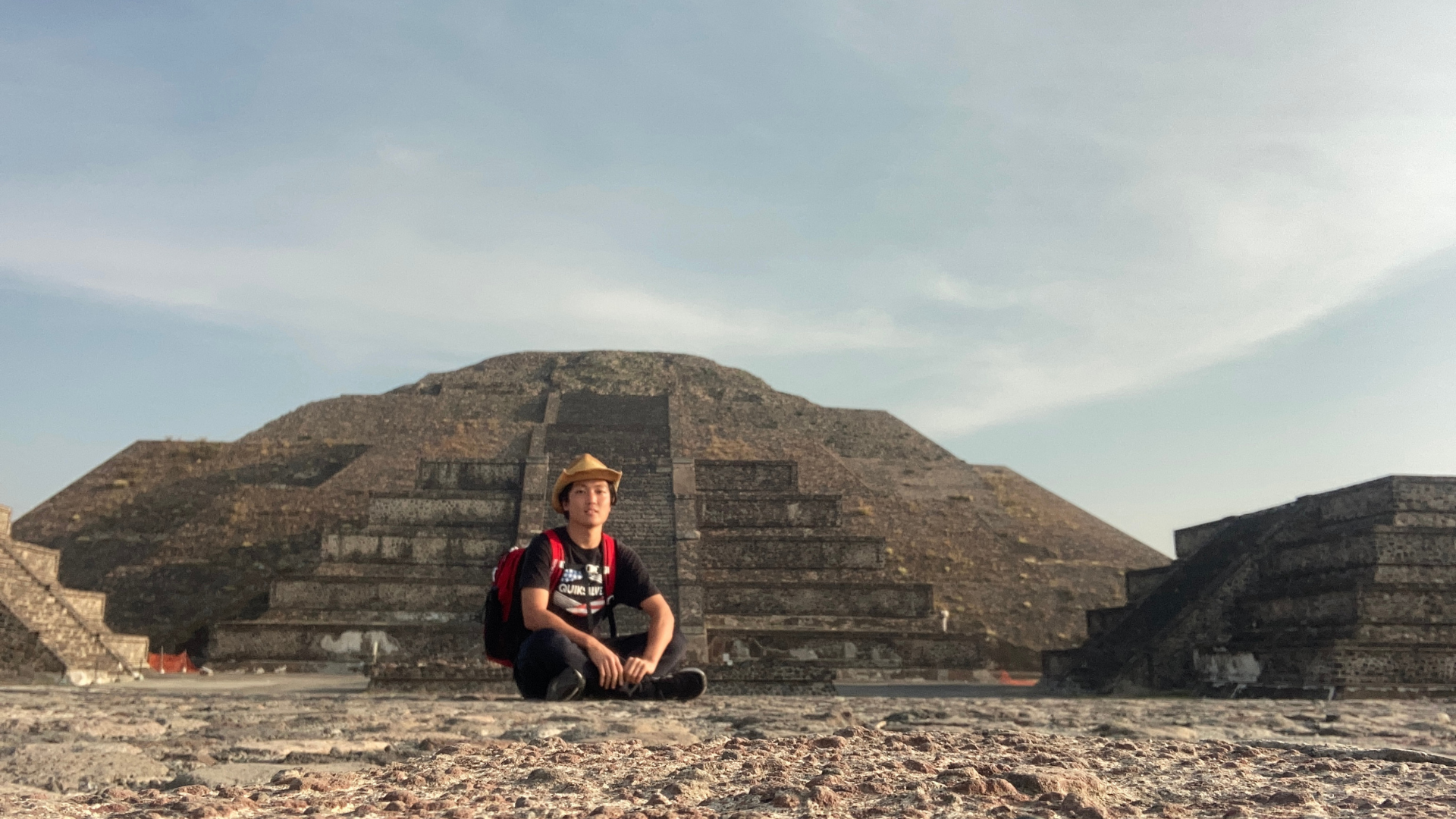 メキシコのテオティワカン遺跡を背景に地面に座るリッキーさん