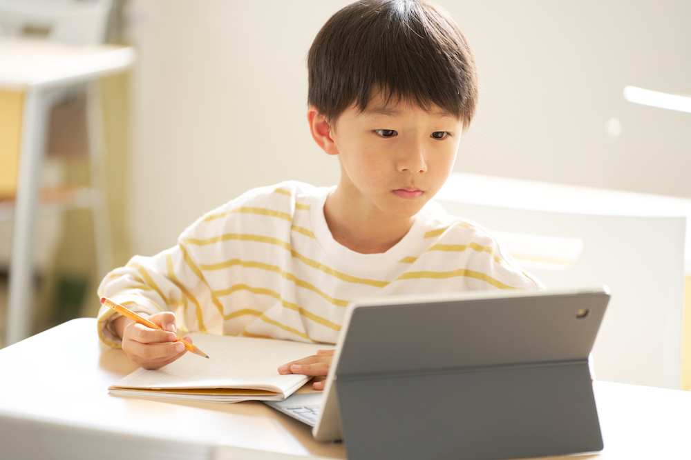 タブレットと鉛筆で自分のペースで学ぶ小学生の様子