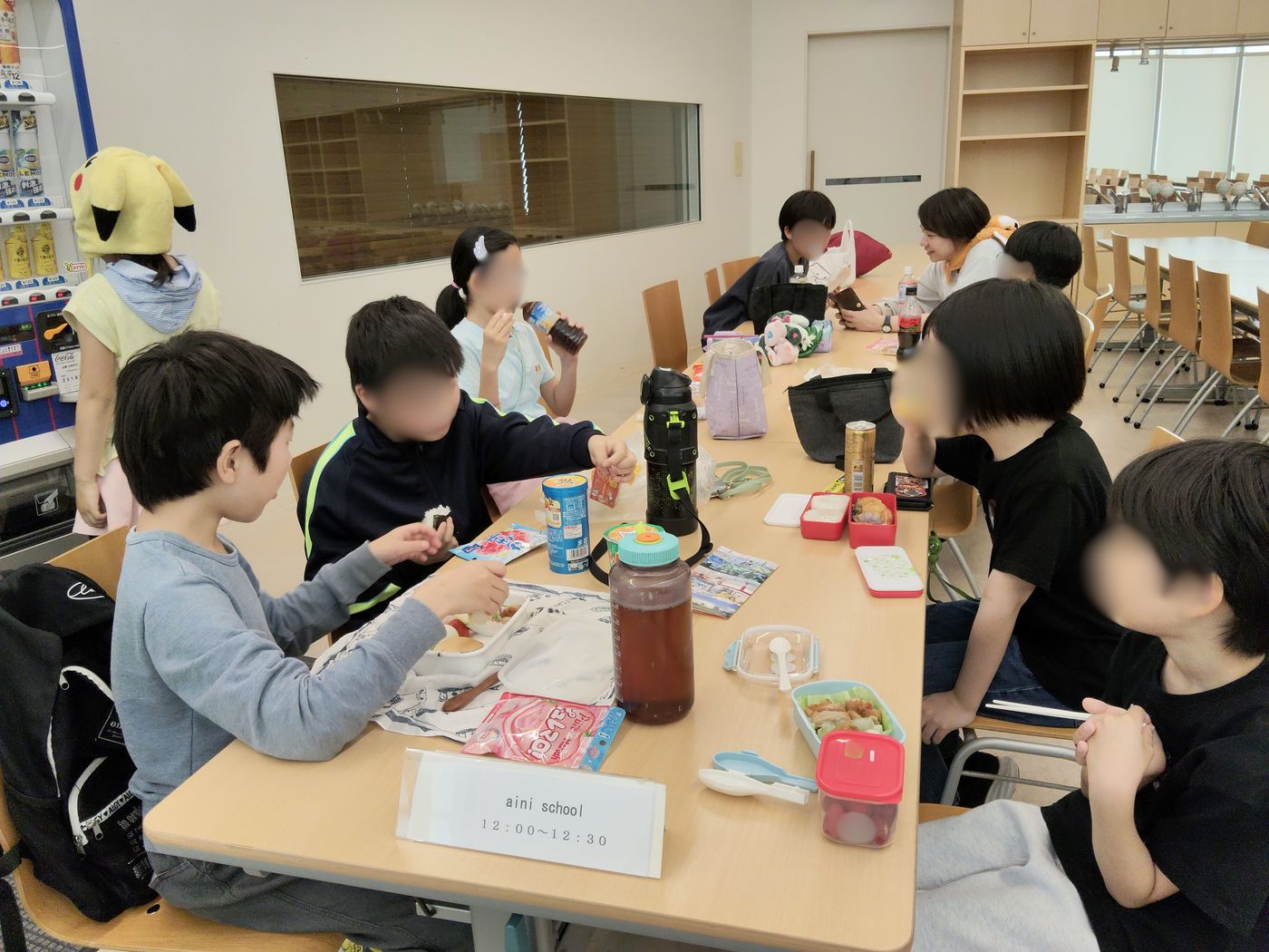 ガスの科学館の食堂でお弁当を広げてランチをするaini schoolの子どもたちと保護者