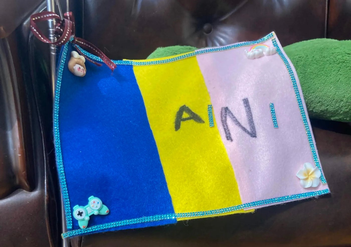 aini schoolのブランドカラーで手作りされたフェルトの旗、ビーズ縁取りや小さな飾りがついている