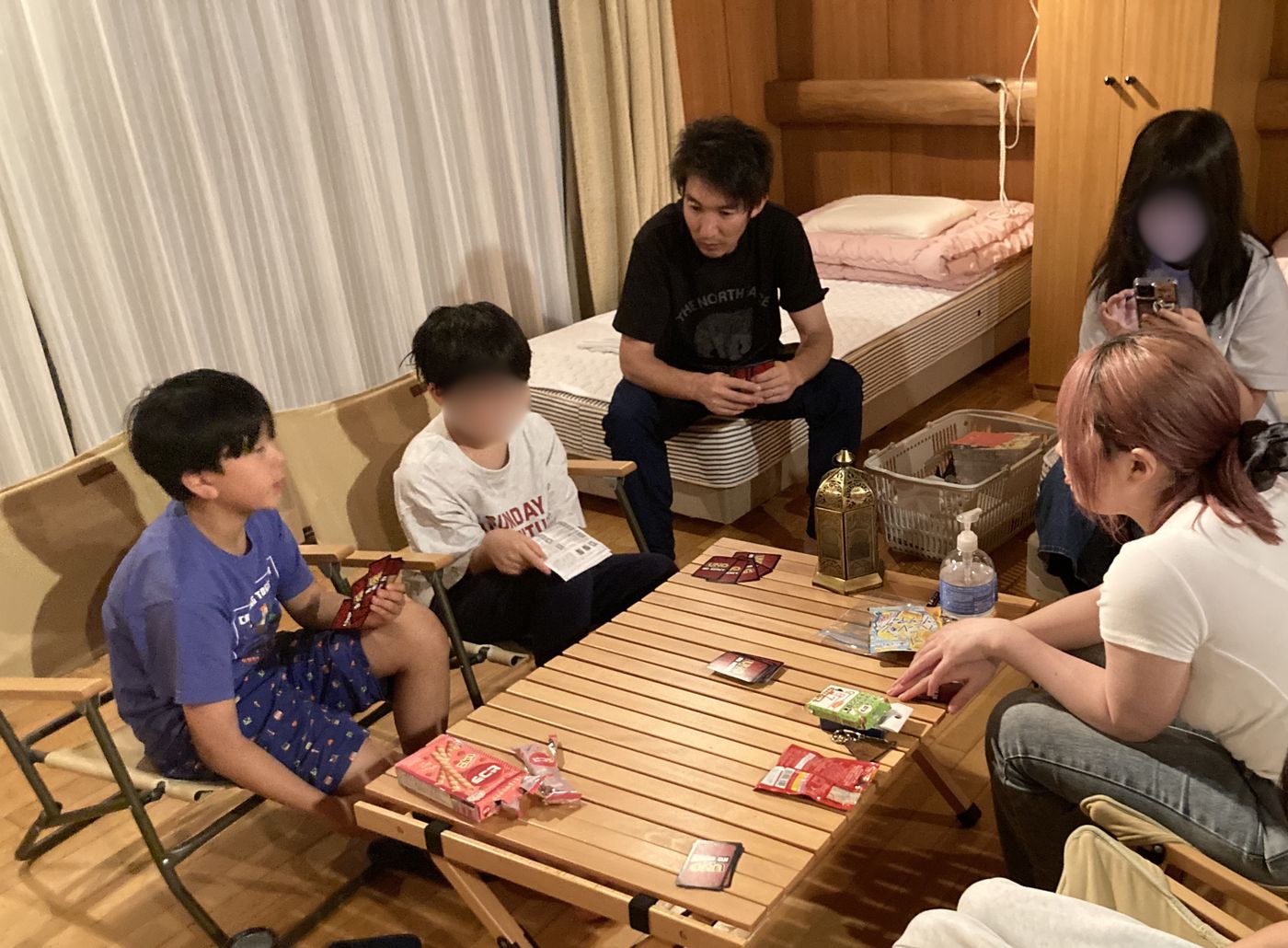 YMCAの室内でローテーブルを囲み、スタッフと子どもたちがカードゲームを楽しむ様子