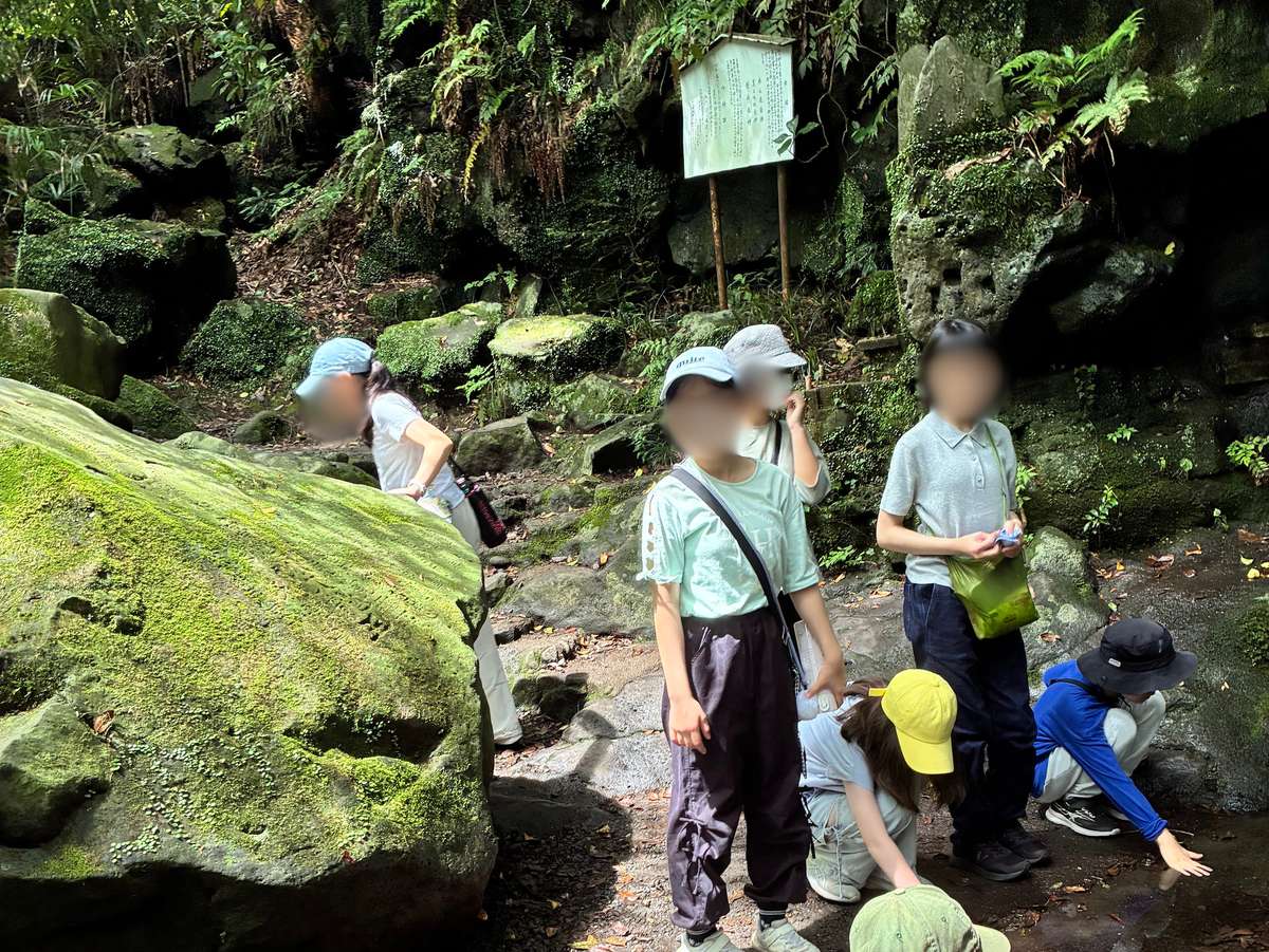 白糸の滝近くの岩場で富士山の湧水に触れるaini schoolの生徒たち